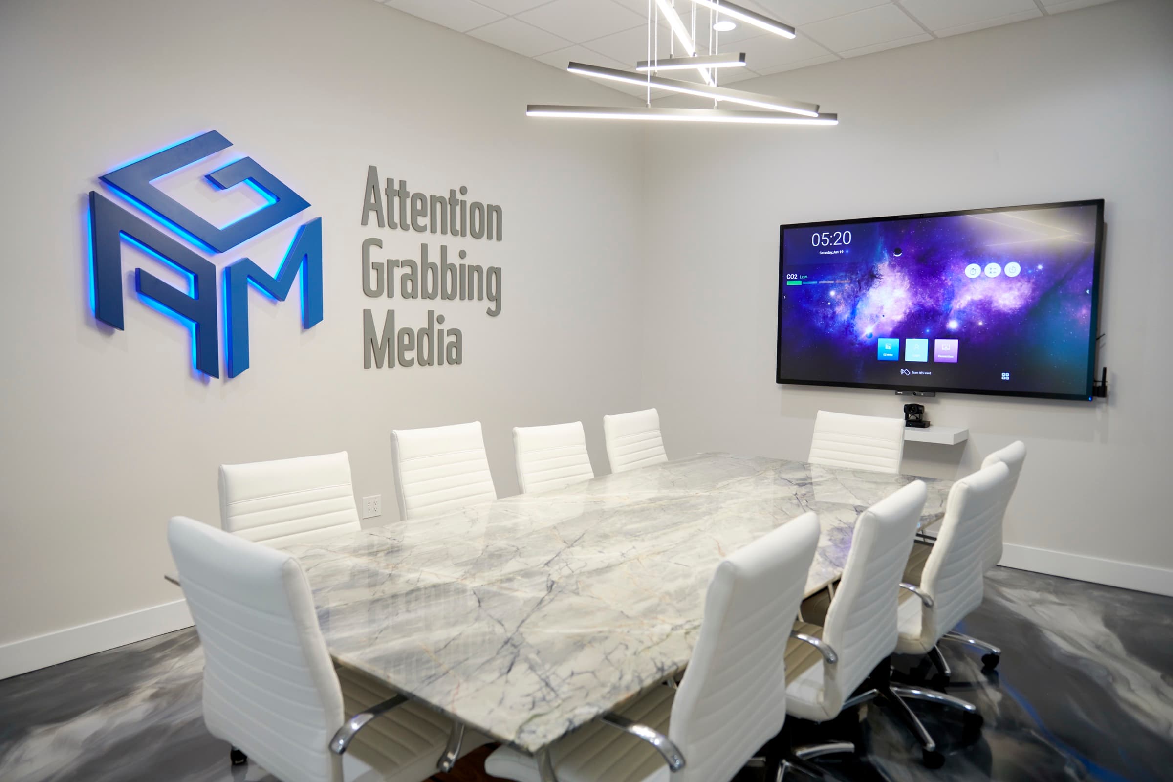 AGM HQ conference room where strategy sessions run, branded wall and screen