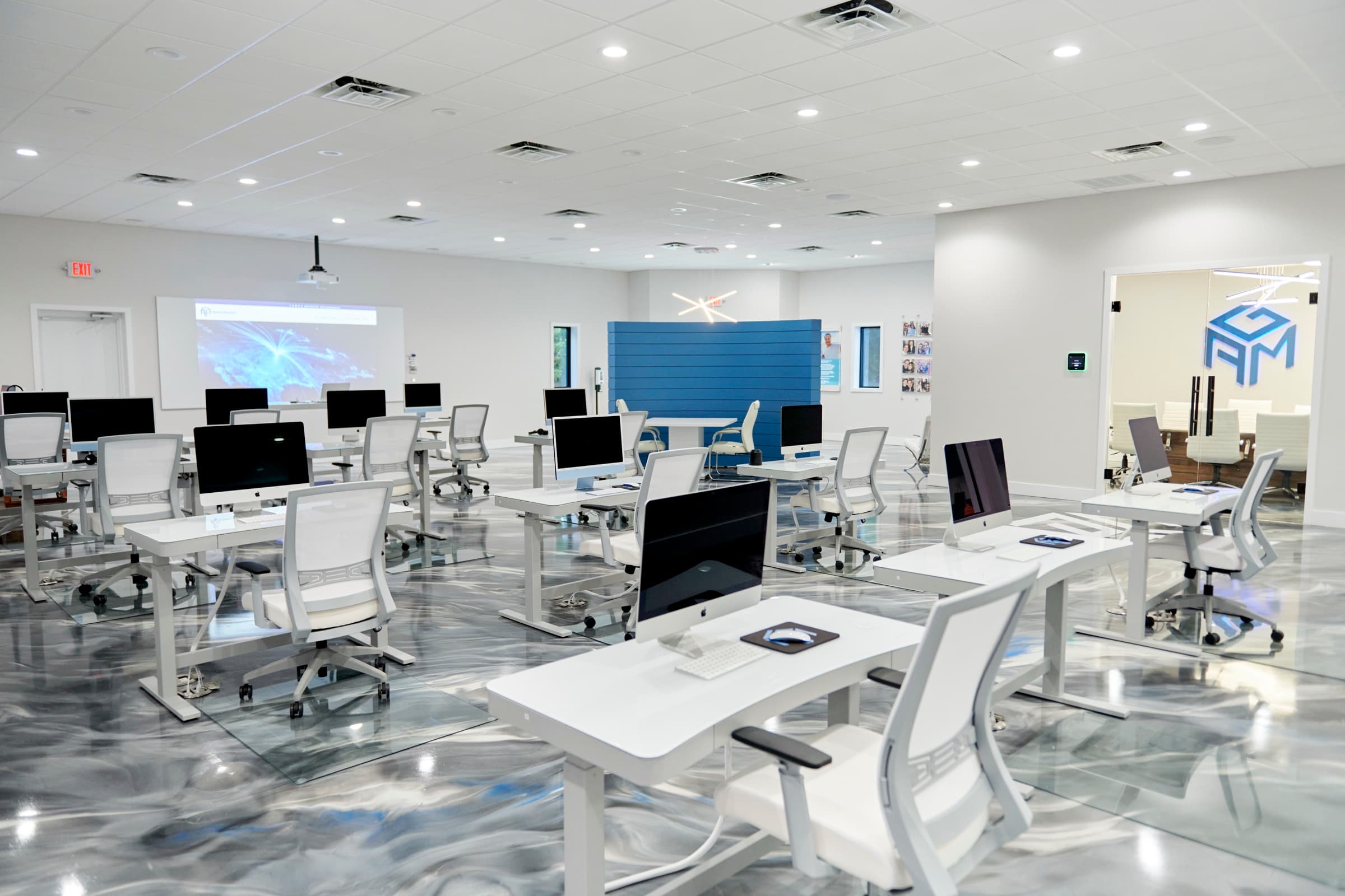 AGM open office: iMac rows with a live website projected on the wall screen