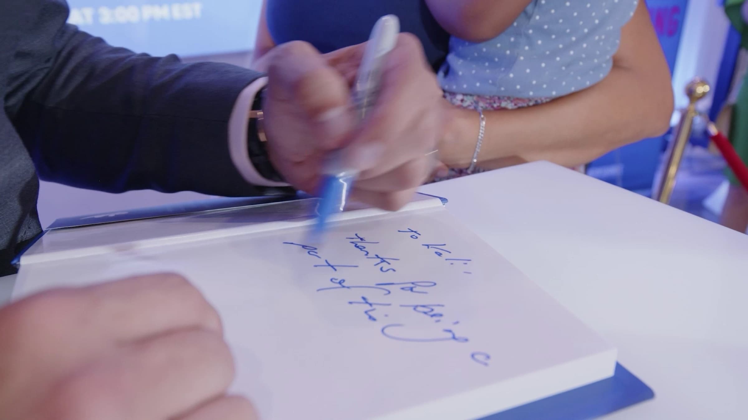 Close-up of hands signing a copy of Marketing Magic
