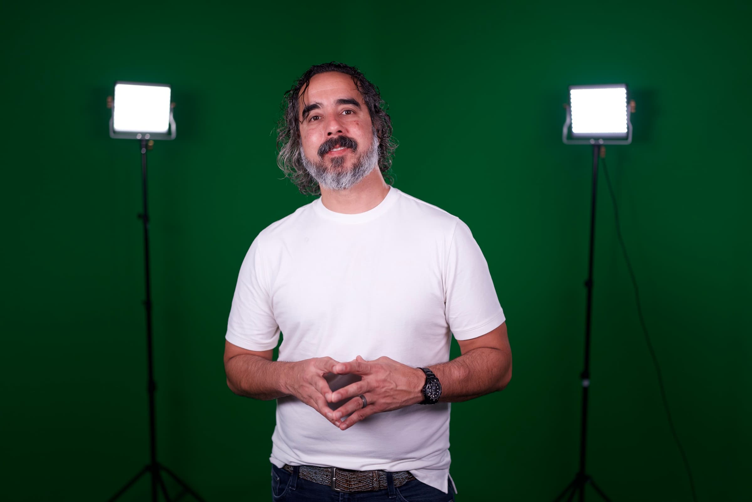 Manuel between two panel lights on the green-screen studio set