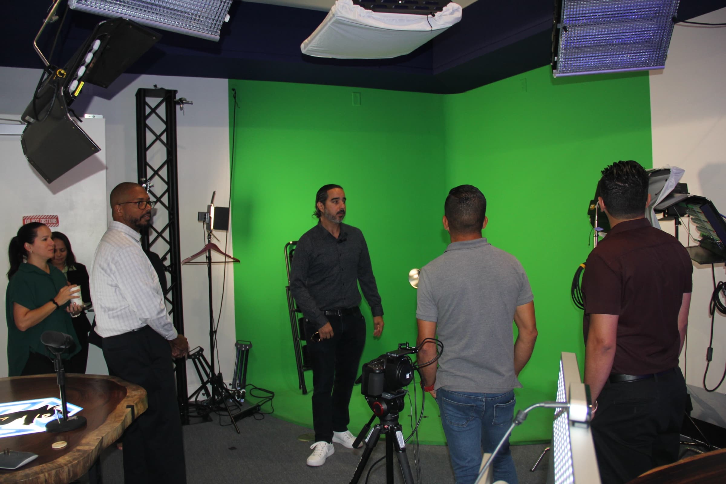 A shoot in progress at the green-screen wall, camera rolling, Manuel directing