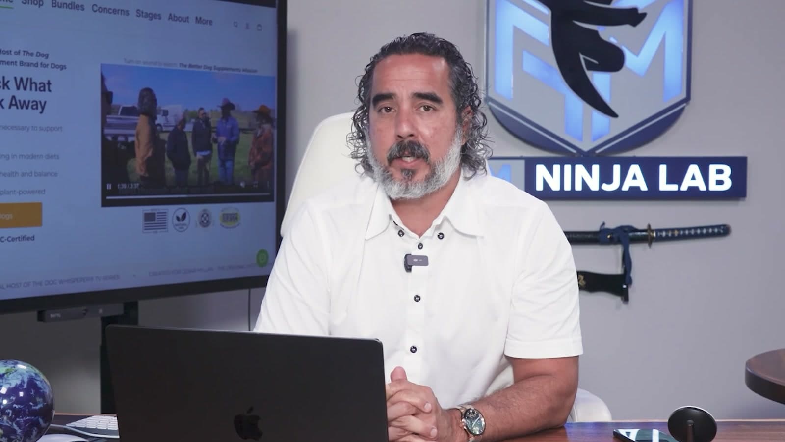 Manuel talking to camera at the AI-architect desk, live brand storefront on screen behind