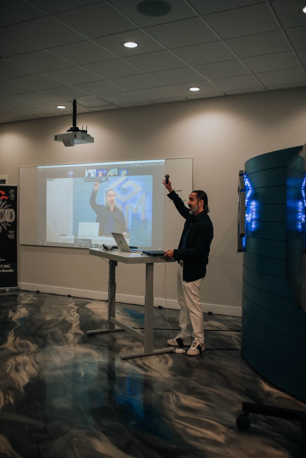 Manuel mid-lesson at the 2024 AI Mastermind, arm raised beside his live projection