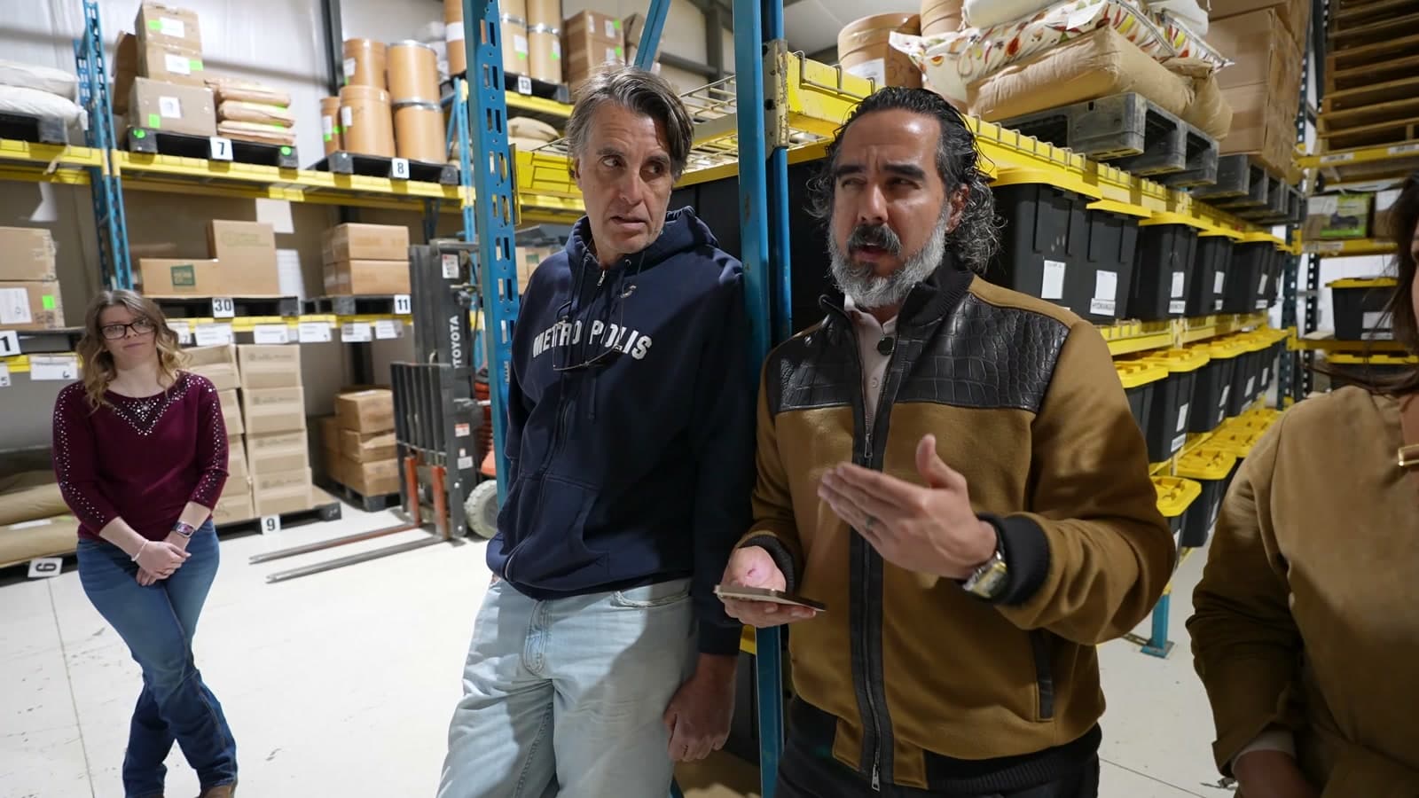 Manuel mid-conversation on the warehouse floor in front of stocked pallet racking