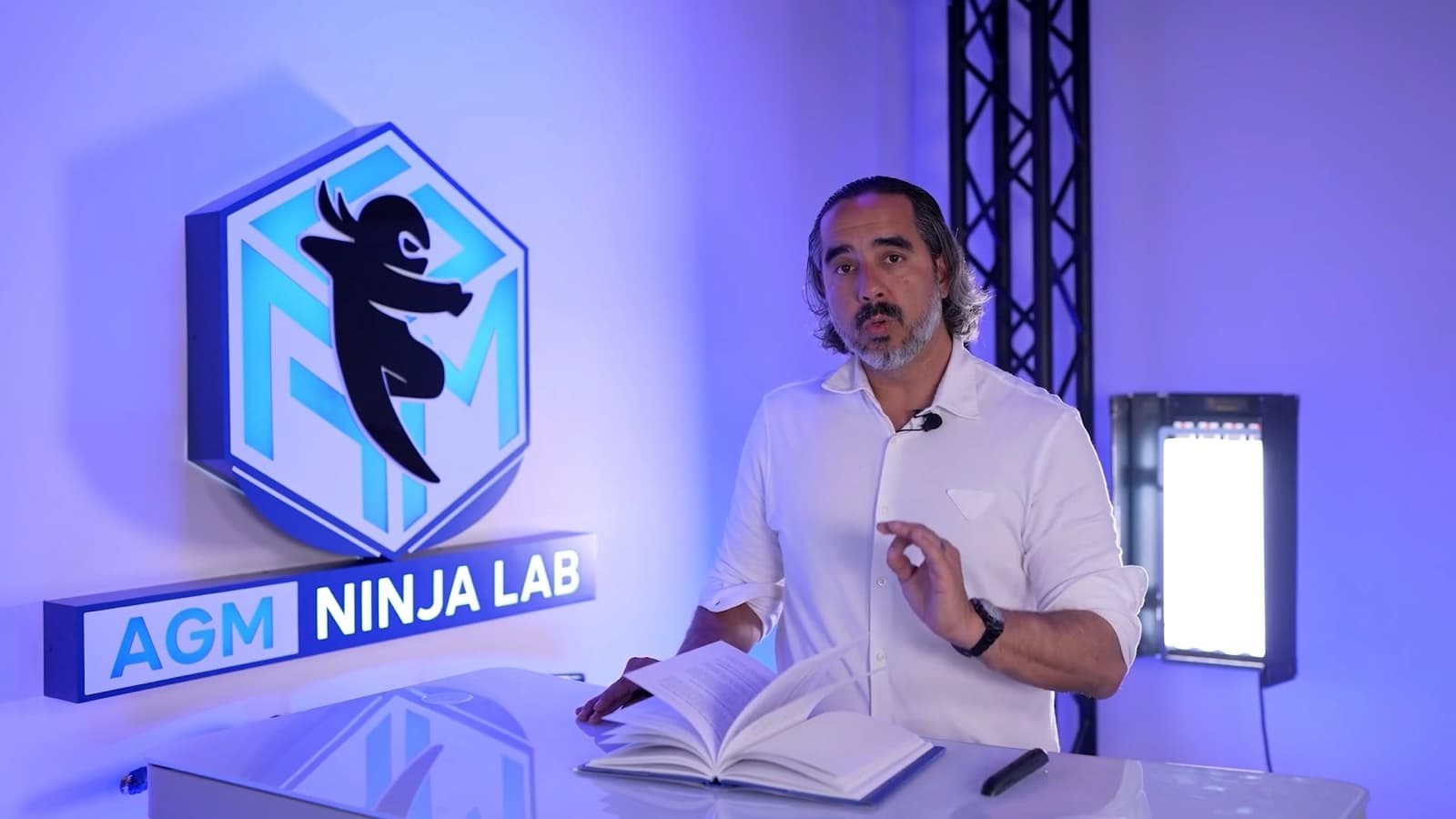 Manuel on camera at the Ninja Lab desk, studio light and truss in frame