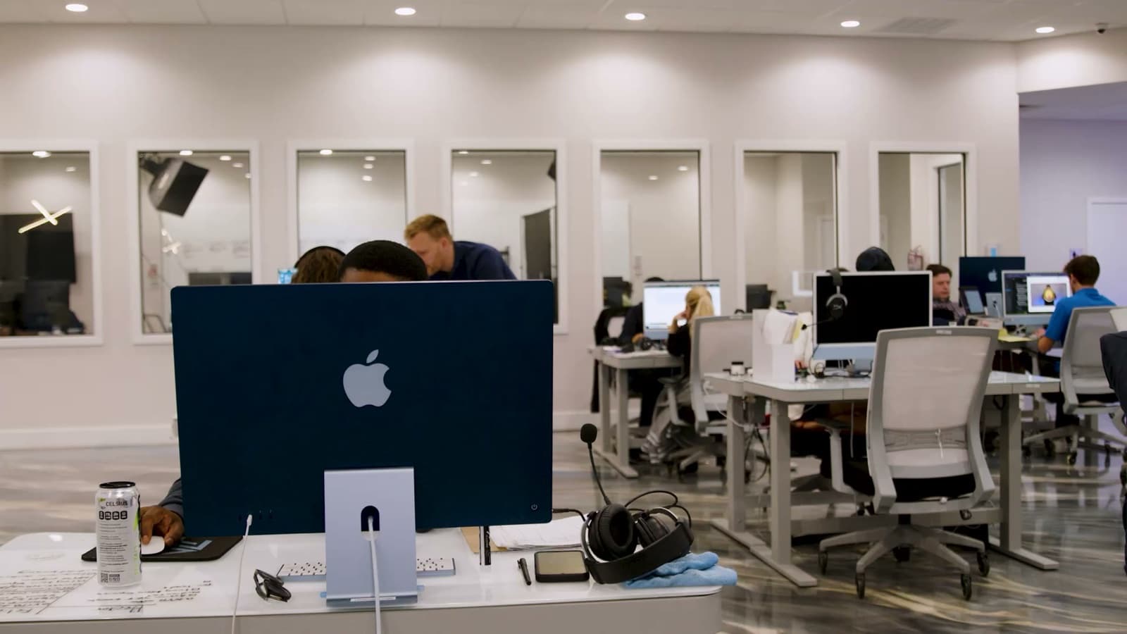 The AGM floor at work: team at iMacs, a designer building product creative on screen